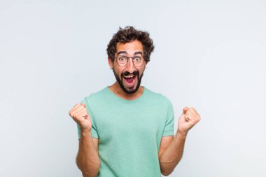 Genç sakallı adam şok olmuş, heyecanlı ve mutlu hissediyor, gülüyor ve başarıyı kutluyor,!