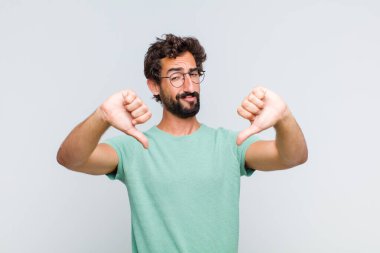 Genç sakallı adam üzgün, hayal kırıklığına uğramış ya da kızgın görünüyor, anlaşmazlık içinde parmaklarını gösteriyor, hayal kırıklığına uğramış hissediyor.