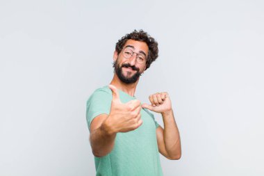 Genç sakallı adam gururlu, kaygısız, kendinden emin ve mutlu, olumlu gülümsüyor.