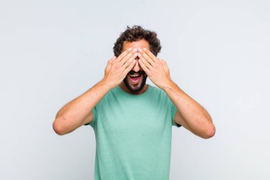 Genç sakallı adam gülümsüyor ve mutlu hissediyor, iki eliyle gözlerini kapatıyor ve inanılmaz bir sürpriz bekliyor.