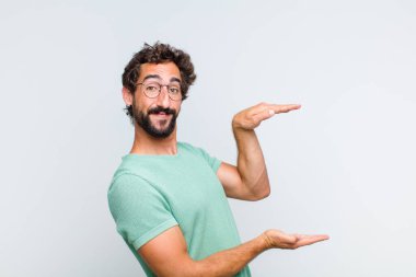 Genç sakallı adam gülümsüyor, mutlu, pozitif ve memnun, fotokopi alanında nesne ya da konsept tutuyor ya da gösteriyor