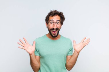 Genç sakallı adam mutlu, heyecanlı, şaşırmış ya da şok olmuş hissediyor. İnanılmaz bir şeye gülümsüyor ve hayrete düşüyor.