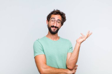 Genç sakallı adam gururla ve güvenle gülümsüyor, mutlu ve tatmin olmuş hissediyor ve fotokopi alanında bir konsept gösteriyor.