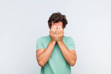 Genç sakallı adam üzgün, hayal kırıklığına uğramış, gergin ve depresif, iki eliyle yüzünü kaplayan, ağlayan