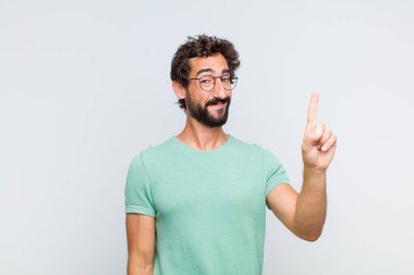 Genç sakallı adam gülümsüyor ve arkadaş canlısı görünüyor, bir numara ya da ilk eli önde, geriye doğru sayıyor.