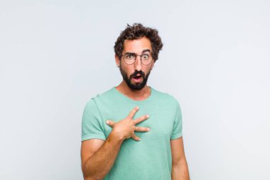 Genç sakallı adam şok olmuş, şaşırmış ve şaşırmış hissediyor, elleri göğsünde ve ağzı açık, kim olduğunu söylüyor, ben mi??