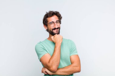 Genç sakallı adam gülümsüyor, hayattan zevk alıyor, mutlu, arkadaş canlısı, tatmin olmuş ve tasasız.