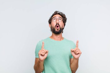 Genç sakallı adam şaşırmış, şaşırmış ve ağzı açık bir şekilde iki elini havaya kaldırıp uzayı kopyalamaya çalışıyor.