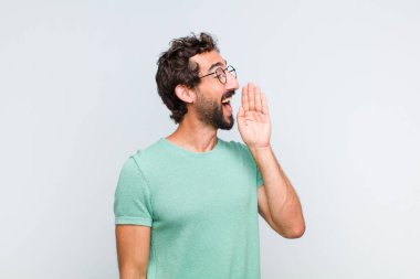 Genç sakallı adam profili, mutlu ve heyecanlı görünüyor, bağırıyor ve kenardaki boşluğu kopyalamak için arıyor.