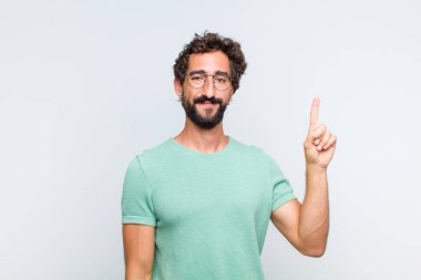 Genç sakallı adam mutlu bir şekilde gülümsüyor, tek eliyle uzayı işaret ediyor.