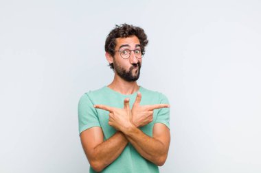 Genç sakallı adam şaşkın ve şaşkın görünüyor, güvensiz ve zıt yönlere şüpheyle bakıyor.