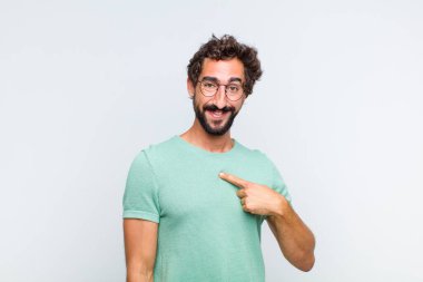 Genç sakallı adam mutlu, gururlu ve şaşırmış görünüyor, neşeli bir şekilde kendini gösteriyor, kendinden emin ve kibirli hissediyor.