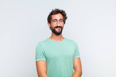 Genç sakallı adam, olumlu ve kendinden emin gülümsüyor. Tatmin olmuş, arkadaş canlısı ve mutlu görünüyor.