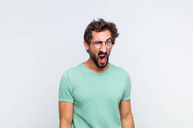 Genç sakallı adam şok olmuş, kızgın, sinirli ya da hayal kırıklığına uğramış, ağzı açık ve öfkeli görünüyor.
