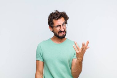 Genç sakallı adam sinirli, sinirli ve hayal kırıklığına uğramış bir halde bağırıyor. 