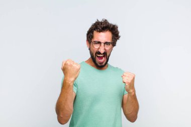 Genç sakallı adam mutlu, şaşırmış ve gururlu hissediyor, bağırıyor ve başarıyı büyük bir gülümsemeyle kutluyor.