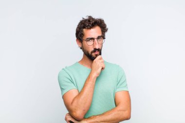 Genç sakallı adam ciddi görünüyor, kafası karışık, kararsız ve düşünceli, seçenekler ve seçimler arasında şüpheci.