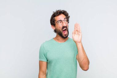 Genç sakallı adam öfkeyle bağırıyor kenardaki boşluğu kopyalasın diye, eli ağzının yanında.