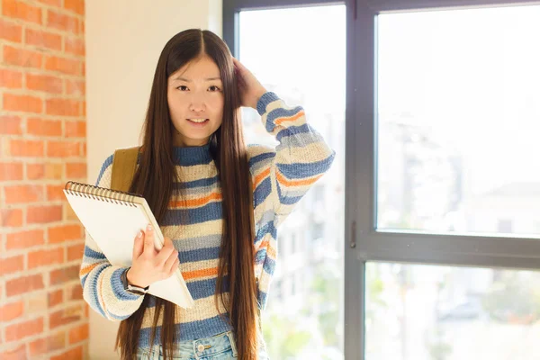 Asyalı genç bir kadın kendini stresli, endişeli, endişeli ya da korkmuş hissediyor. Elleri başının üstünde, hatayla panikliyor.