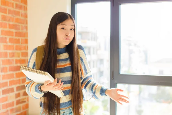 young asian woman feeling clueless and confused, having no idea, absolutely puzzled with a dumb or foolish look