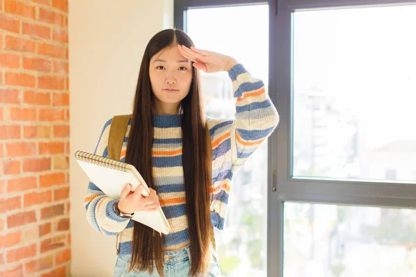 young asian woman greeting the camera with a military salute in an act of honor and patriotism, showing respect