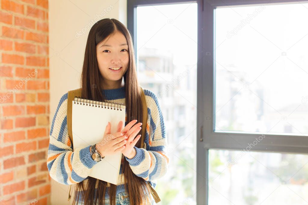 young asian woman feeling happy and successful, smiling and clapping hands, saying congratulations with an applause
