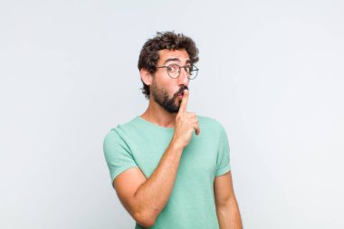 Genç sakallı adam sessizlik ve sessizlik istiyor, parmaklarıyla ağzının önünde işaret ediyor, 