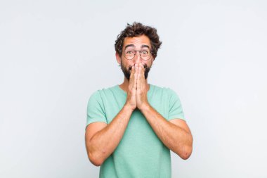 Genç sakallı adam mutlu ve heyecanlı, şaşırmış ve hayrete düşmüş elleriyle ağzını kapatmış, tatlı bir ifadeyle kıkırıyor.
