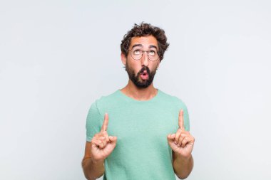 Genç sakallı adam korkuyla ve ağzı açık bir şekilde şaşkın ve şaşkın bir bakışla yukarıya bakıyor.