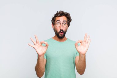 Genç sakallı adam şok olmuş, şaşırmış ve şaşırmış hissediyor. İki eliyle de onay işareti yapıyor.