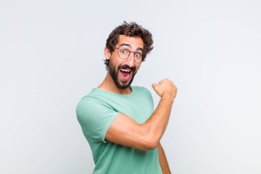 Genç sakallı adam mutlu, pozitif ve başarılı hissediyor, bir meydan okumayla karşılaştığında motive oluyor ya da iyi sonuçları kutluyor.