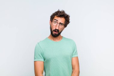 young bearded man feeling puzzled and confused, with a dumb, stunned expression looking at something unexpected