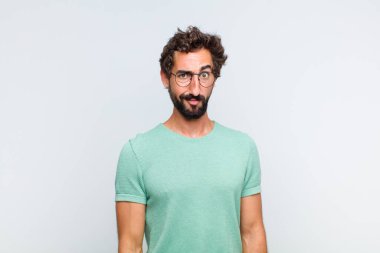 Genç sakallı adam kafası karışık ve şüpheli hissediyor, merak ediyor ya da karar vermeye çalışıyor.