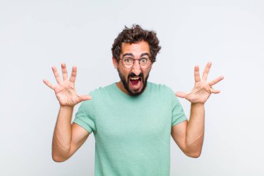 Genç sakallı adam panik ya da öfke içinde bağırıyor, şok olmuş, korkmuş ya da öfkeli, elleri başının yanında.
