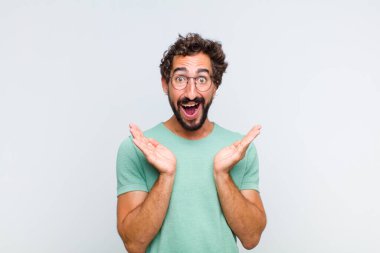 Genç sakallı adam beklenmedik bir sürpriz yüzünden şaşkın ve heyecanlı, gülen, şaşkın ve mutlu hissediyor.