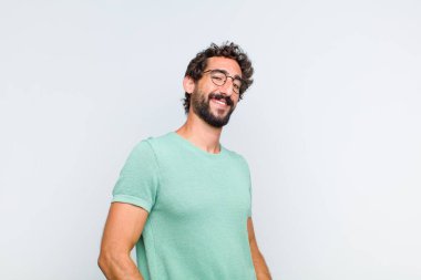 Genç sakallı adam neşeli, neşeli, mutlu, kendinden emin ve rahat bir ifadeyle gülümsüyor.