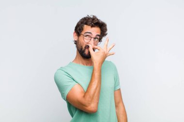 Genç sakallı adam iğreniyor, kötü ve nahoş bir koku almaktan kaçınmak için burnunu tutuyor.