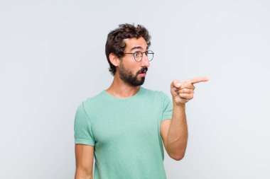 Genç sakallı adam şaşkın ve şaşırmış hissediyor, şaşkınlık içinde hayranlıkla bakıyor ve ona bakıyor.