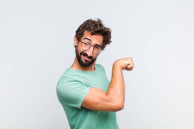 Genç sakallı adam kendini mutlu, tatmin olmuş ve güçlü hissediyor, kaslı ve formda, spor salonundan sonra güçlü görünüyor.