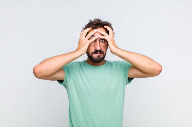 Dehşete kapılmış ve şok olmuş hisseden sakallı genç bir adam, bir hata yüzünden el ele tutuşup panikliyor.