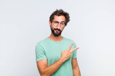 Genç sakallı adam mutlu, pozitif ve başarılı hissediyor, göğsünde el yapımı V ile, zafer ya da barış gösteriyor.