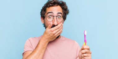 Genç sakallı adam elleri ile ağzını kapatıyor, şok olmuş, şaşırmış bir ifadeyle, bir sır saklıyor ya da 