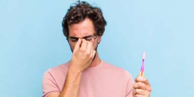 Genç sakallı adam stresli, mutsuz ve hayal kırıklığına uğramış, alınlı ve şiddetli baş ağrısı çeken.