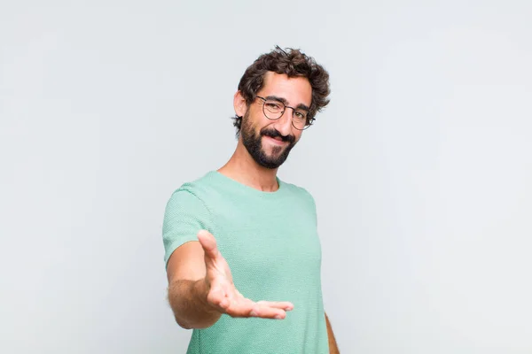 stock image young bearded man smiling, looking happy, confident and friendly, offering a handshake to close a deal, cooperating