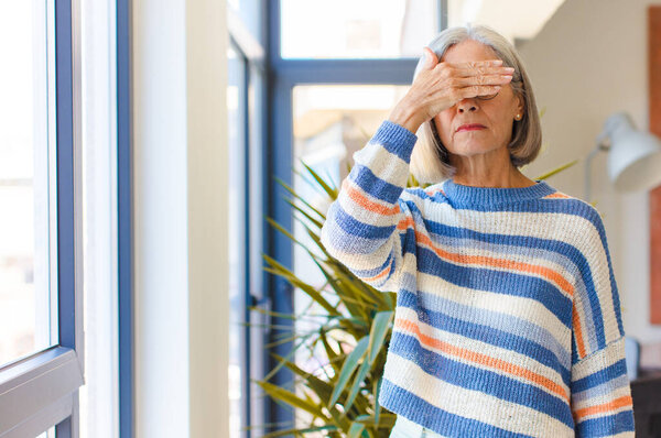 middle age woman covering eyes with one hand feeling scared or anxious, wondering or blindly waiting for a surprise