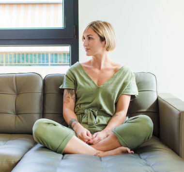 Güzel sarışın kadın bilgisiz ve kafası karışık, bir çözüm düşünüyor, eli kalçasında, diğeri kafasında, dikiz aynasından.