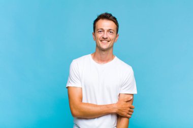 Genç yakışıklı adam utangaç ve neşeli bir şekilde gülüyor, arkadaş canlısı ve olumlu ama güvensiz bir tavırla.