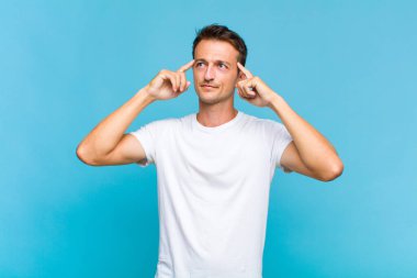 Genç ve yakışıklı bir adam kafası karışmış ya da şüphe içinde, bir fikre odaklanmış, çok düşünüyor, kenarda boşluğu kopyalamaya çalışıyor.