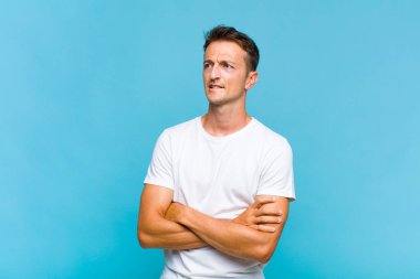 Genç yakışıklı adam şüphe ediyor ya da düşünüyor, dudağını ısırıyor ve kendini güvensiz ve gergin hissediyor, kenarda yer arıyor.