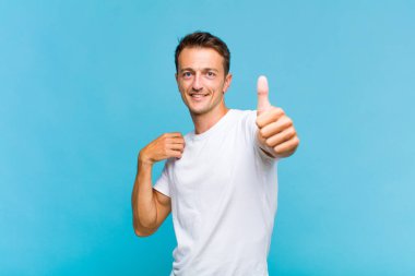 Genç yakışıklı, gururlu, tasasız, kendinden emin ve mutlu, başparmaklarıyla gülümseyen.